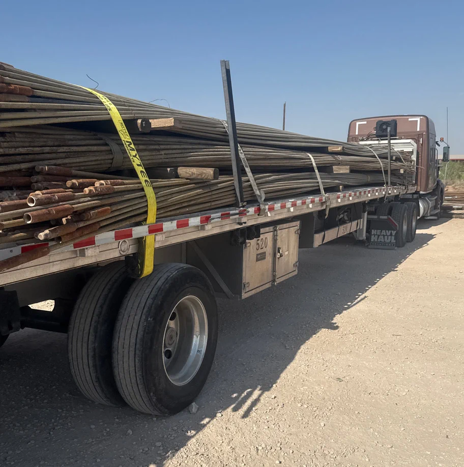 A photograph of a flat bed truck hauling sucker rods.