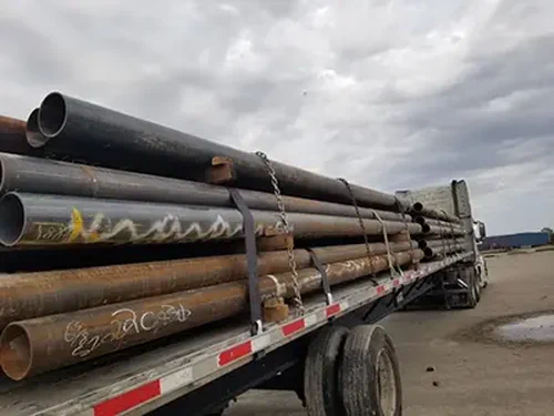 A photo of a semi truck loaded with oil pipes.