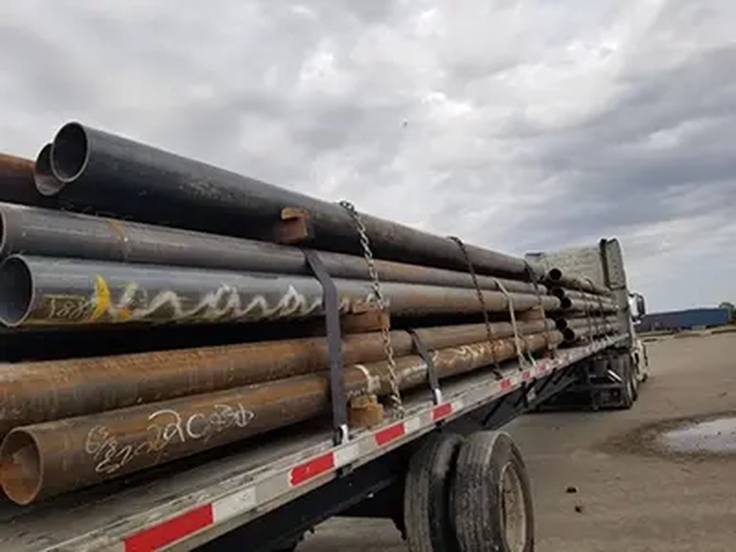 A photo of a semi truck loaded with oil pipes.