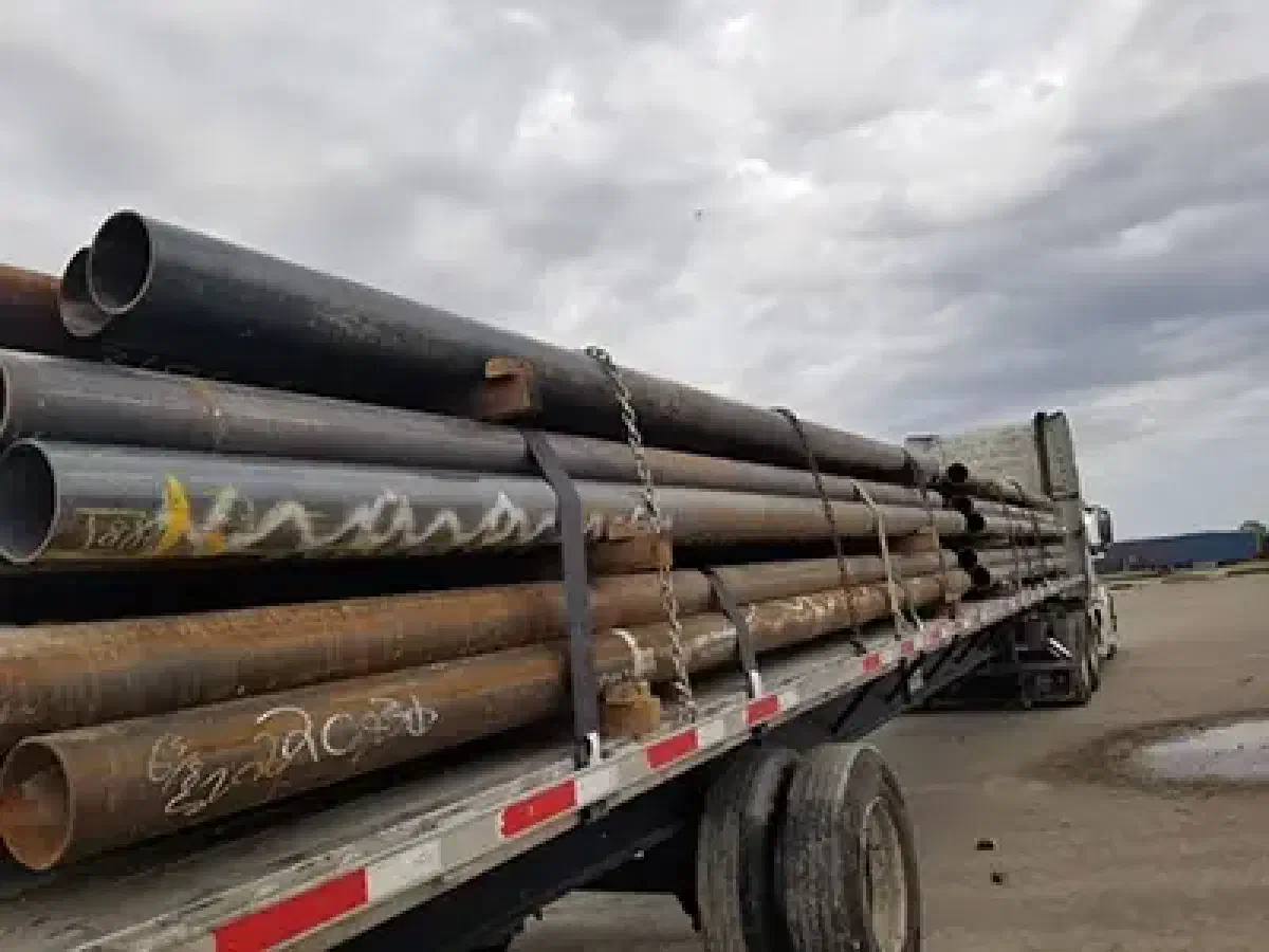 A photo of a semi truck loaded with oil pipes.