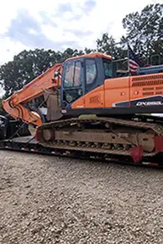 Photo of a semi truck hauling a large construction backhoe.