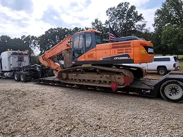A photograph of a semi truck hauling a backhoe.