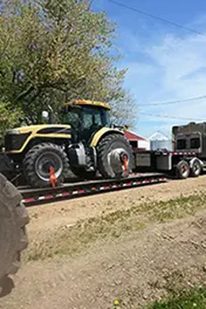 Photo of a semi truck hauling a large agricultural tractor.